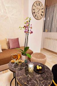 Iaki Apartment Mamaia في مامايا: غرفة معيشة مع طاولة وساعة على الحائط