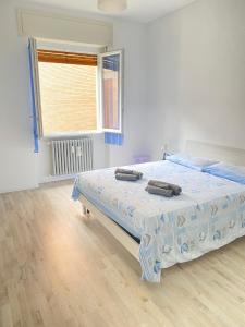 ein weißes Schlafzimmer mit einem Bett, auf dem zwei Gegenstände liegen in der Unterkunft Casa Manolo Corsico Navigli Suite Apartment Milan in Corsico