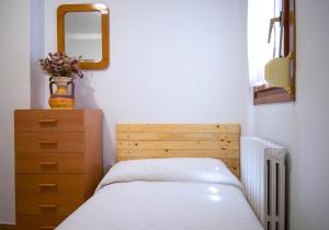een slaapkamer met een bed, een dressoir en een spiegel bij Casa El Soldau in Naval