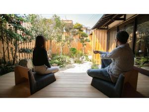 un hombre y una mujer sentados en sillas en un patio en Kominka Hotel kurasu - Vacation STAY 24260v en Tatsuno
