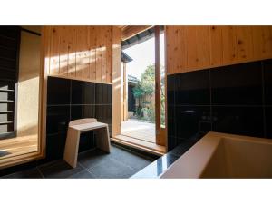 a bathroom with a tub and a stool in it at Kominka Hotel kurasu - Vacation STAY 24260v in Tatsuno