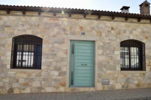 - un bâtiment en pierre avec une porte verte et 2 fenêtres dans l'établissement Casa Rural, El Retorno, à Santa Elena
