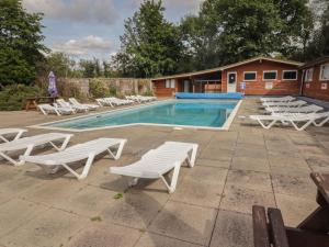 uma piscina com espreguiçadeiras brancas e uma piscina em The Bird House em Newcastle Emlyn