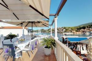 a balcony with tables and chairs and a view of the water at Radovani Luxury Apartment with Private Pool in Jelsa