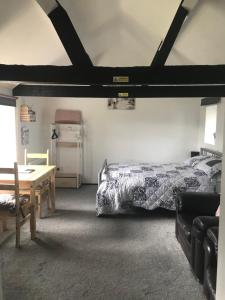 een slaapkamer met een bed, een tafel en een bank bij Robyns Nest, self catering cottage in Welshpool