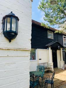 a light on the side of a house with tables and chairs at 4 Bed 17th century Coach House in Brasted