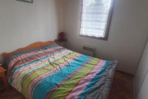 Un dormitorio con una cama con un edredón colorido. en Chalet dans un parc résidentiel de loisir - 0102, en Soulac-sur-Mer