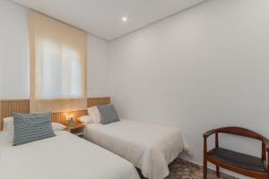 una habitación de hotel con 2 camas y una silla en Manolete apartamento, en Jerez de la Frontera