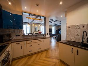 a large kitchen with white cabinets and a wooden floor at Duplex Jeanne d'Arc Billard Baby en option Escape Game Logements Insolites in Nancy