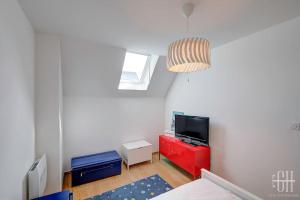een woonkamer met een tv en een rode dressoir bij L'ardoise / Proche Centre in Fondettes