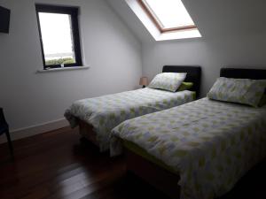 two beds in a room with two windows at Claddaghaduff 371 Omey Lodge in Claddaghduff