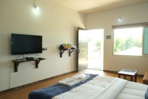 1 dormitorio con 1 cama y TV de pantalla plana en la pared en Amigos Lake Resort-Igatpuri, en Igatpuri