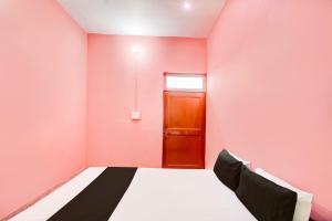 a bedroom with a pink wall and a bed at SPOT ON THE SWEET DREAM HOTEL in Alīgarh