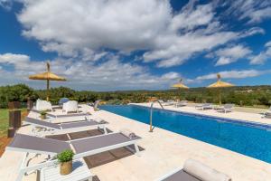 una piscina con tumbonas y sombrillas en un patio en Campos -2795 Mallorca, en Campos