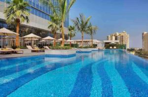 einem großen Pool mit Palmen und einem Gebäude in der Unterkunft Extravagant Palm Studio In 5-star Hoteloceanview in Dubai
