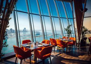 ein Restaurant mit Tischen und Stühlen und Blick auf das Wasser in der Unterkunft Extravagant Palm Studio In 5-star Hoteloceanview in Dubai