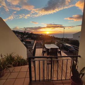 a balcony with a table and chairs and a sunset at Villa&Damata in Água de Pena