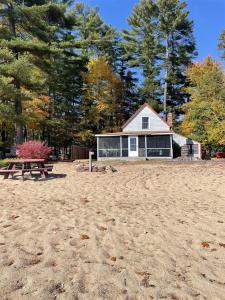 a house on the beach with a picnic table at 1901 HOUSE LIMIT 10 cottage in North Sebago