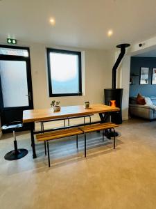 una mesa y bancos en una habitación con chimenea en THE SHARE HOUSE, en Tillé