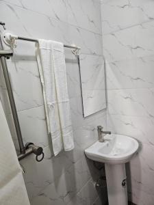 Baño blanco con lavabo y espejo en Glory Apartment en Ibadán