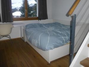 Bett in einem Zimmer mit einem Schreibtisch und einem Stuhl in der Unterkunft Alpine Lodge Parc Linard in Lenzerheide