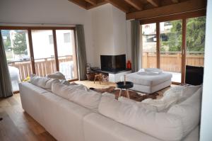 a living room with a white couch and a television at Alpine Lodge Parc Linard in Lenzerheide