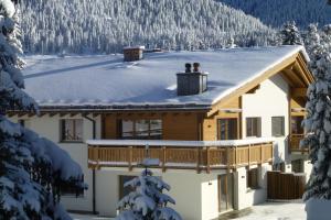 a house with a deck in the snow at Alpine Lodge Parc Linard in Lenzerheide