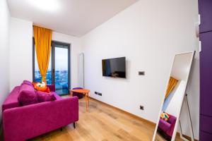 een woonkamer met een paarse bank en een tv bij CheckBelgradeApartments - Colors in Belgrado