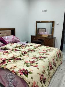 una camera da letto con un letto con un piumone floreale e uno specchio di APPARTEMENT AMINE a Delmonte