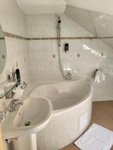 ein Badezimmer mit einer weißen Badewanne und einem Waschbecken in der Unterkunft Hotel Margit in Trenčianske Teplice
