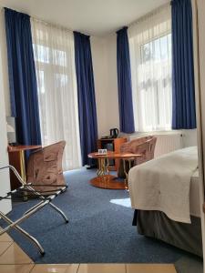 Schlafzimmer mit blauen Vorhängen, einem Bett und einem Tisch in der Unterkunft Hotel Margit in Trenčianske Teplice