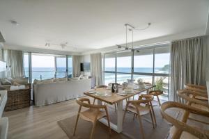 a dining room with a table and chairs and a living room at Cashelmara Beachfront Apartments in Gold Coast