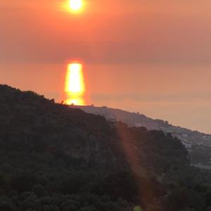 una puesta de sol sobre una colina con la puesta de sol en Villa in campagna con piscina, en San Fratello