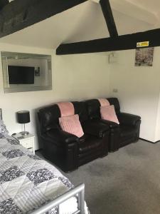Cette chambre comprend un canapé en cuir noir et une télévision. dans l'établissement Robyns Nest, self catering cottage, à Welshpool