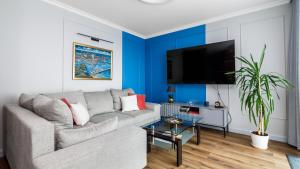 ein Wohnzimmer mit einem grauen Sofa und einer blauen Wand in der Unterkunft VENTI Św. Piotra 6 GDYNIA in Gdynia