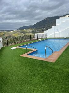 une grande piscine avec clôture et pelouse verdoyante dans l'établissement Ático con increíbles vistas a las montañas y mar, à Frigiliana