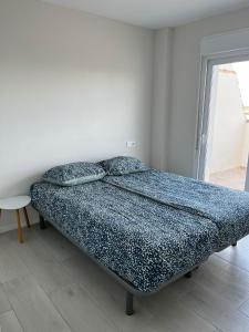 Schlafzimmer mit einem Bett mit blauer Bettwäsche und Kissen in der Unterkunft Casa de la Madera in San Pedro del Pinatar