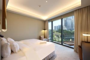 - une chambre avec un grand lit blanc et une grande fenêtre dans l'établissement Livbnb 3BR w/ Burj Khalifa View, Heart of Downtown, à Dubaï