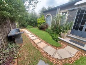 een tuin met een stenen loopbrug voor een huis bij Lieu De Grace in Johannesburg