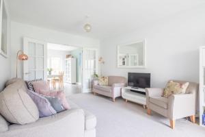 ein Wohnzimmer mit einem Sofa, 2 Stühlen und einem TV in der Unterkunft Detached 4-Bed home - Idyllic Village in Cambridge