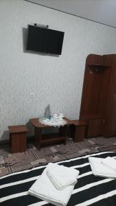 Habitación con mesa y TV en la pared. en Готель Ассоль en Khmelʼnytsʼkyy