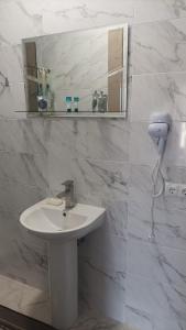 ein weißes Badezimmer mit einem Waschbecken und einem Spiegel in der Unterkunft Готель Ассоль in Chmelnyzkyj