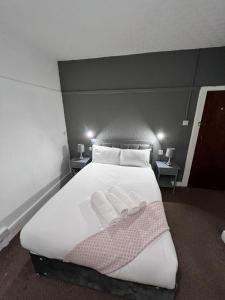 a bedroom with a white bed with two slippers on it at Harbour Hotel in Skegness