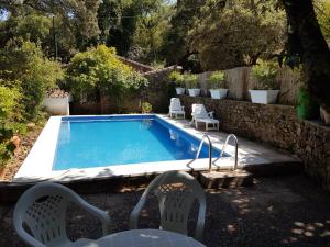 a swimming pool with two chairs and a table at Casa del escultor in Canaleja