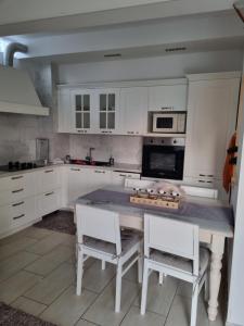 uma cozinha com armários brancos e uma mesa com cadeiras em Residence Hotisstyle em Portorož
