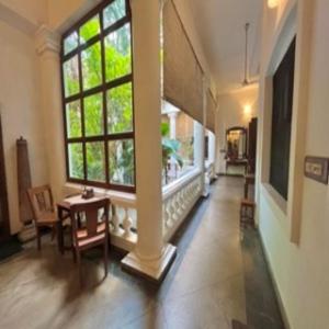een hal met een groot raam en een tafel en stoelen bij La Maison de Bitasta in Pondicherry
