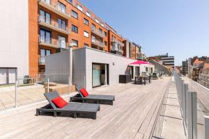 une terrasse en bois avec des chaises et des tables dans un bâtiment dans l'établissement Sunny apartment in Knokke-Heist with big terrace, à Knokke-Heist