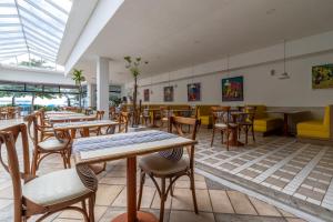 un restaurante con mesas y sillas en una habitación en Ingleses Praia Hotel, en Florianópolis