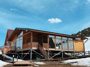 a wooden house with glass windows and stairs at ALTO Cabins in Alamedin
