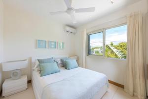 a white bedroom with a bed and a large window at Seafront apt breathtaking view in Cap Malheureux in Cap Malheureux